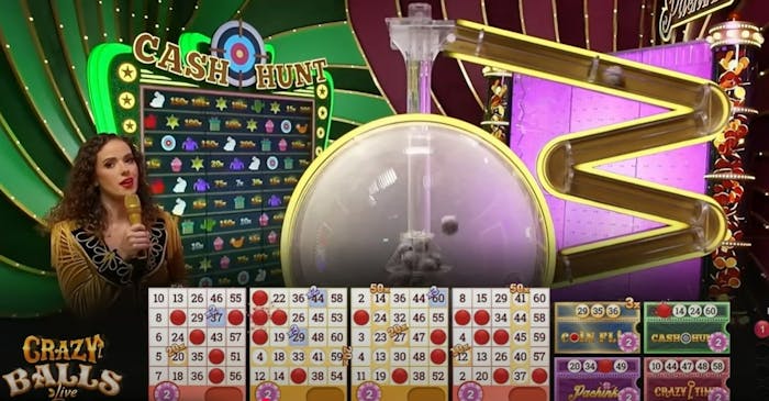 Nainen juontaa Evolutionin Crazy Balls Live bingopeliä - Ruudulla on bingokortteja ja useita värikkäitä peliosioita.